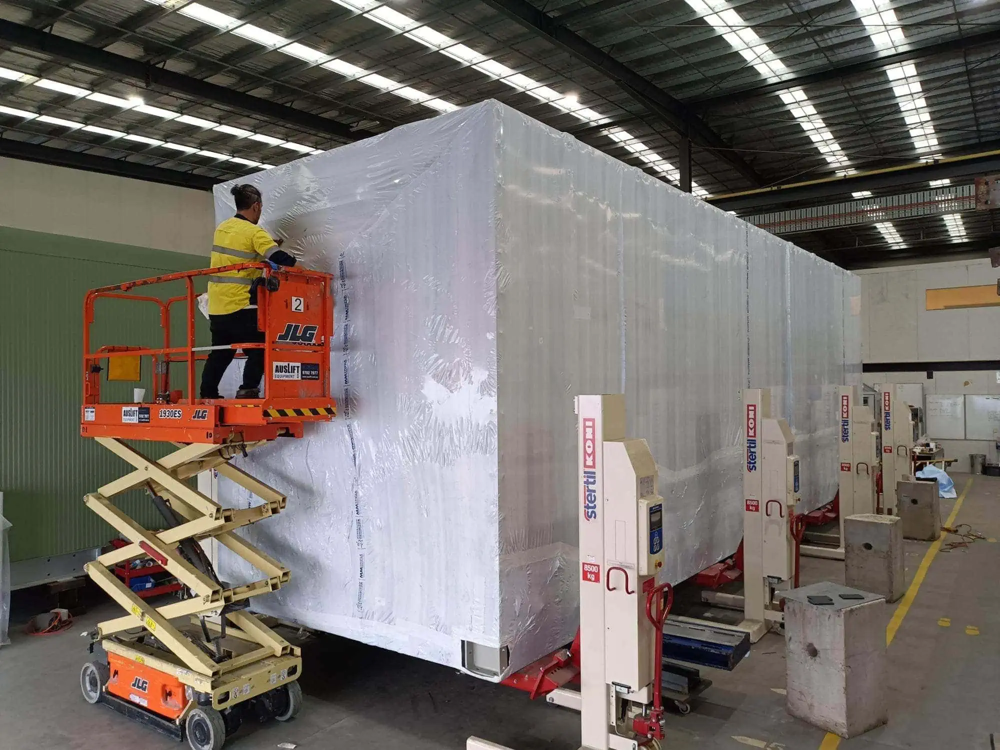 worker shrink wrapping large machine